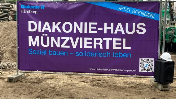 Auf einer Baustelle steht ein großes Plakat mit der Aufschrift "Diakonie-Haus Münzviertel". © Susanne Röhse 