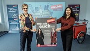 Heike Sudmann (l.) und Cansu Özdemir, Spitzenkandidatinnen der Partei Die Linke, präsentieren die Plakat-Kampagne der Linken zur Bürgerschaftswahl in Hamburg. © picture alliance / dpa Foto: Markus Scholz