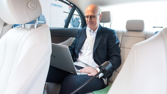 Peter Tschentscher (SPD), Erster Bürgermeister von Hamburg, sitzt nach einem Termin in seinem Dienstwagen am Laptop und arbeitet. © picture alliance/dpa Foto: Daniel Bockwoldt