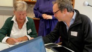 Digitalmentor Michael Böhnert und der Rentnerin Karin Laschet sitzen an einem Tisch. © NDR Foto: Jenny Witt