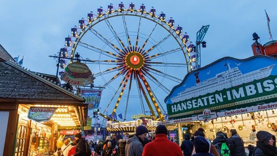 Das Riesenrad auf dem Winterdom in Hamburg ist im Hintergrund zusehen, davor sind Imbiss-Buden. © picture alliance / dpa Foto: Markus Scholz