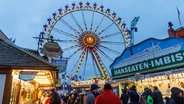 Das Riesenrad auf dem Winterdom in Hamburg ist im Hintergrund zusehen, davor sind Imbiss-Buden. © picture alliance / dpa Foto: Markus Scholz