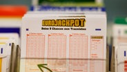 Eurojackpot Spielscheine stehen in einem Regal in einer Lotto-Annahmestelle. © picture alliance Foto: Thomas Banneyer