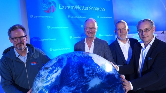 Eckart von Hirschhausen (v.l.n.r.), Sven Plöger, Tobias Fuchs und Frank Böttcher halten nach der Eröffnungspressekonferenz des 14. Extremwetterkongresses in der Hafencity Universität Hamburg einen Globus hoch. © Marcus Brandt/dpa Foto: Marcus Brandt