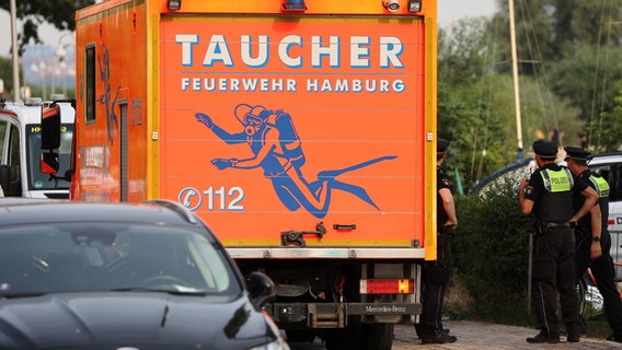 Polizisten stehen neben einem Fahrzeug der Taucherstaffel der Hamburger Feuerwehr. (Archivfoto) © Bodo Marks/dpa 