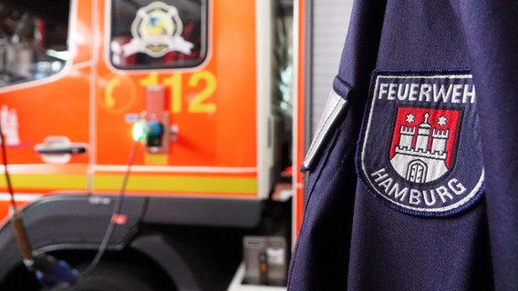 Eine Jacke mit der Aufschrift "Feuerwehr Hamburg" und ein Feuerwehrauto in der Feuer- und Rettungswache Berliner Tor. © dpa-Bildfunk Foto: Julian Weber
