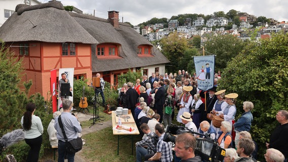 Einige Menschen haben sich zur Eröffnungsfeier des historischen Fischerhauses Blankenese versammelt. © picture alliance Foto: Christian Charisius