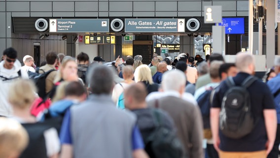 Reisende stehen in einer langen Schlange vor der Sicherheitskontrolle am Hamburger Flughafen an. © picture alliance/dpa Foto: Bodo Marks