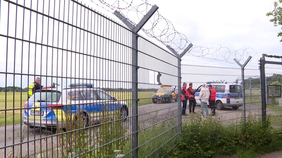 Polizei und Flughafenpersonal stehen an einem Zaun. © TV Newskontor Foto: Screenshot