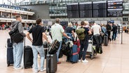 Flugreisende schauen auf einer Tafel am Hamburger Flughafen nach ihren Flügen. © picture alliance/dpa Foto: Markus Scholz