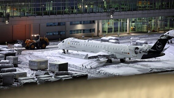 Eine mit Schnee bedeckte Maschine der Lufthansa steht auf dem verschneiten Münchener Flughafen. © dpa bildfunk Foto: Karl-Josef Hildenbrand