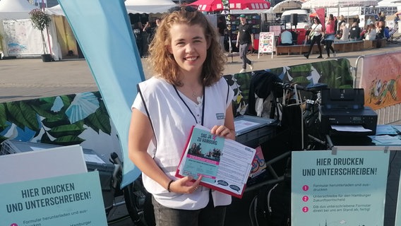 Annika Rittmann von Fridays for Future steht an einem Stand für den Hamburger Zukunftsentscheid. © NDR Info Foto: Marc-Oliver Rehrmann