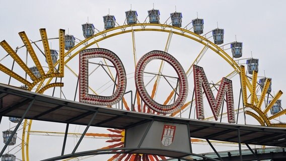 Das Riesenrad auf dem Heiligengeistfeld ist hinter dem Schriftzug "Dom" zu sehen. © picture alliance/dpa Foto: Marcus Brandt
