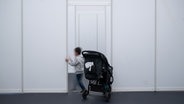 Ein Junge spielt in einem Ankunftszentrum hinter einem Kinderwagen. © picture alliance/dpa Foto: Sebastian Gollnow