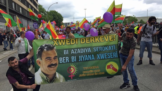 Kurden aus ganz Deutschland kommen zum Demonstrieren in Hamburg zusammen und halten ein Banner hoch. © NDR Foto: Susanne Röhse