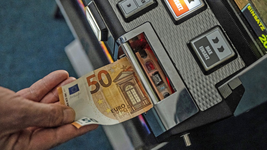 Ein Geldschein wird in einen Glücksspielautomat geschoben.