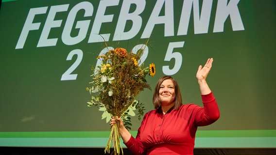 Katharina Fegebank steht bei der Landesmitgliederversammlung der Grünen mit einem Blumenstrauß auf der Bühne. © Georg Wendt/dpa 