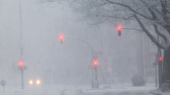 Nur wenige Fahrzeuge sind bei starkem Schneefall auf einer Hauptverkehrsstraße unterwegs. Die Sicht ist durch den Schnee stark eingeschränkt. © dpa-Bildfunk Foto: Christian Charisius