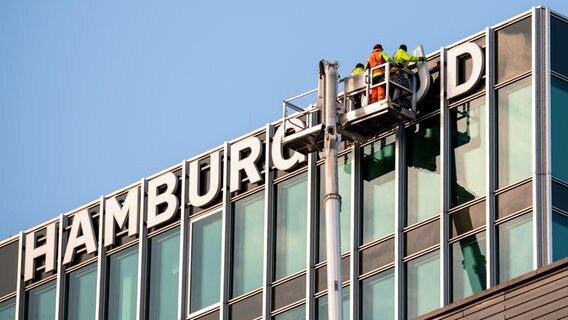 Der Schriftzug „Hamburg Süd“ wird am ehemaligen Hauptsitz der gleichnamigen Reederei mit Hilfe einer Teleskopmastbühne abgebaut. © dpa Foto: Daniel Bockwoldt