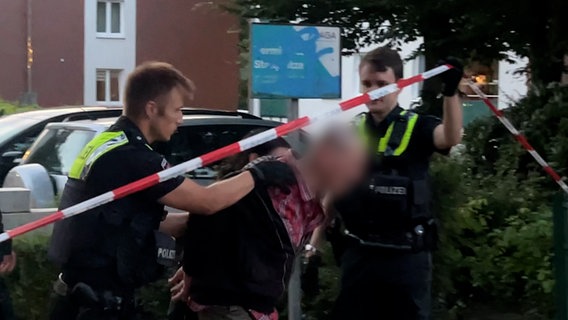 Ein Mann wird von der Polizei abgeführt. © Elias Bartl / NDR Foto: Screenshot