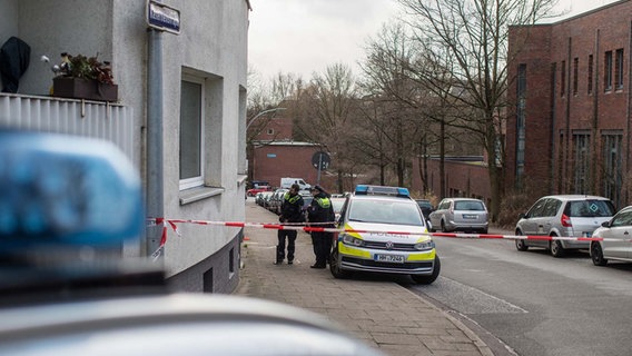 Zwei Polizisten stehen vor einem Hauseingang in Harburg. Dort wurde eine tödlich verletzte Frau auf dem Fußweg gefunden. © BlaulichtNews 