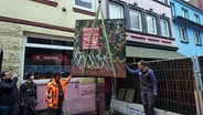 Ein Teilstück der Sichtschutzanlage aus dem Jahr 1933 am östlichen Eingang der Herbertstraße im Hamburger Stadtteil St. Pauli wird mit einem Kran weggehoben. © picture alliance / dpa Foto: Marcus Brandt