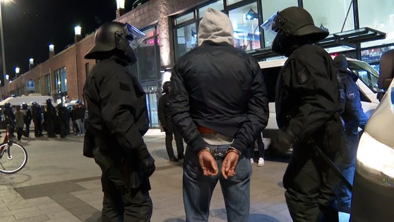 Ein Tatverdächtiger steht vor dem Bahnhof Bergedorf in Handschellen. © TV News Kontor Foto: Screenshot