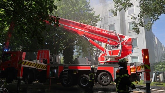 Einsatzkräfte der Feuerwehr sind in Hamburg-Hummelsbüttel im Einsatz, wo ein Dachstuhl brennt. © dpa Foto: Christian Charisius