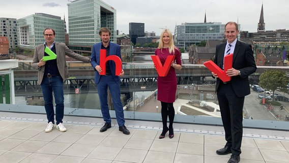 Hochbahn-Chef Henrik Falk, Verkehrsbehörden-Staatsrat Martin Bill (Grüne), HVV-Chefin Anna-Theresa Korbutt und der Landrat des Kreises Herzogtum Lauenburg, Christoph Mager, (v.l.n.r.) halten die Buchstaben des neuen HVV-Logos in der Hand. © NDR Foto: Reinhard Postelt