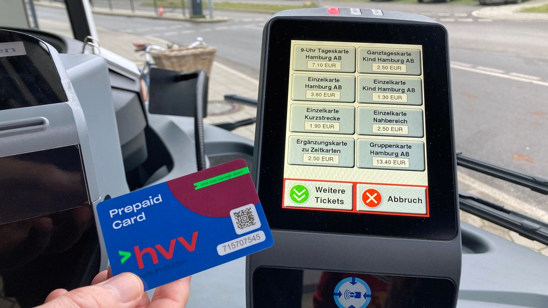 Eine Hand hält eine Prepaid-Karte des HVV vor ein Lesegerät in einem Bus in Hamburg.