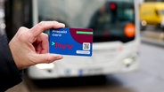 Eine Person hält eine Prepaid-Karte des HVV vor einen Bus. © picture alliance 