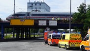 Mehrere Einsatzwagen stehen vor einer Brücke, auf der ein ICE steht. © Citynews 