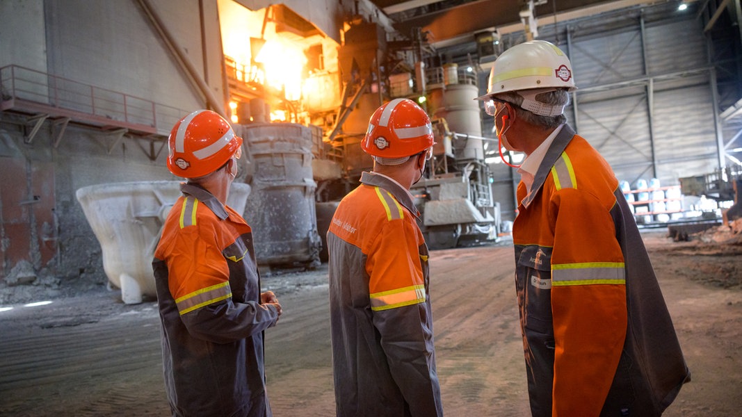 Drei Männer stehen vor einem Elektrolichtbogenofen im Stahlwerk der ArcelorMittal GmbH.