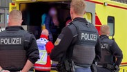 Zwei Polizisten stehen vor einem Rettungswagen. © TVNewskontor/ DSLR News 