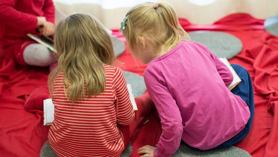 Zwei Mädchen lesen in einer Kita in Hamburg in einem Buch. © dpa Foto: Daniel Reinhardt