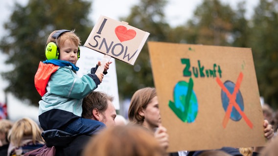 Ein Junge sitzt bei einer Demonstration in Hamburg auf den Schultern seines Vaters und hält ein Schild mit der Aufschrift: "I Love Snow." © picture alliance/dpa Foto: Christian Charisius