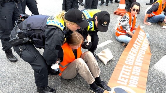 Mehrere Personen der Gruppe "Letzte Generation" blockieren eine Straße in Hamburg. © NDR Foto: Finn Kessler