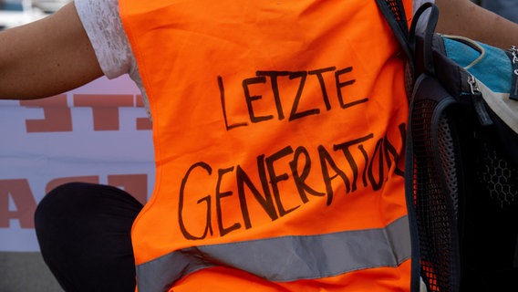 Ein Aktivist mit einer Warnweste mit der Aufschrift "Letzte Generation". © picture alliance Foto: Michael Bihlmayer