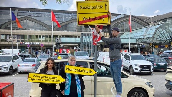 Mitglieder der Linken in Hamburg zeigen vor dem Hauptbahnhof Schilder, mit denenn sie gegen den Umgang mit Obdachlosen und Drogenabhängigen protestieren. © NDR Foto: Susanne Röhse