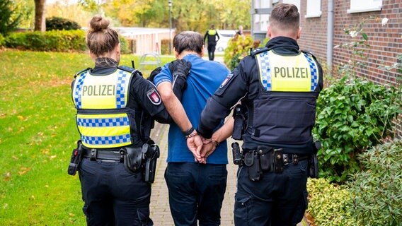 Eine Polizistin und ein Polizist führen im Stadtteil Lohbrügge einen Mann ab. © Daniel Bockwoldt/dpa 
