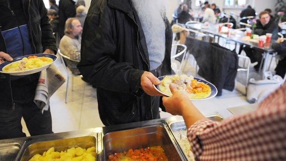 Odachlose stehen in Hamburg in der Obdachlosentagesstätte "MAhlZEIT" in Hamburg-Altona für ein warmes Mittagessen an. © picture alliance / dpa 