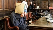 Der Angeklagte verbirgt sein Gesicht im Gerichtssaal, wo es um Kriegsverbrechen einer syrischen Regierungsmiliz geht. © dpa-Bildfunk Foto: Markus Scholz