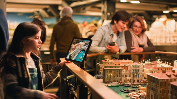 Ein Mädchen sieht sich auf einem Tablet im Miniatur Wunderland eine Simulation zum Kimawandel an. © Miniatur Wunderland/Telekom 