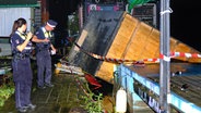 Hamburger Polizisten stehen am Einsatzort in Moorfleet am Holzhafen, nachdem eine Hausboothütte von Schwimmponton bei einem Gewittersturm geweht wurde. © picture alliance/dpa Foto: Carsten Neff