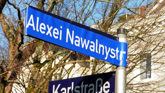 Unbekannte haben auf einem Straßenschild mit dem Namen "Am Feenteich" einen blauen Aufkleber mit der Aufschrift "Alexei Nawalnystr." geklebt. © picture alliance/dpa/CitynewsTV 