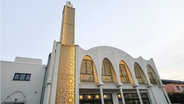 Außenansicht und Zierminarett der Bait-ur-Rasheed Moschee in Hamburg-Stellingen. Das Hauptgebäude ist weiß und das Minarett ist golden. © dpa-Bildfunk Foto: Christian Charisius