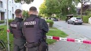 Polizisten stehen im Hamburger Stadtteil Niendorf vor einer Absperrung. Im Hintergrund ist ein Auto zu sehen, auf das geschossen wurde. © TV News Kontor Foto: Screenshot