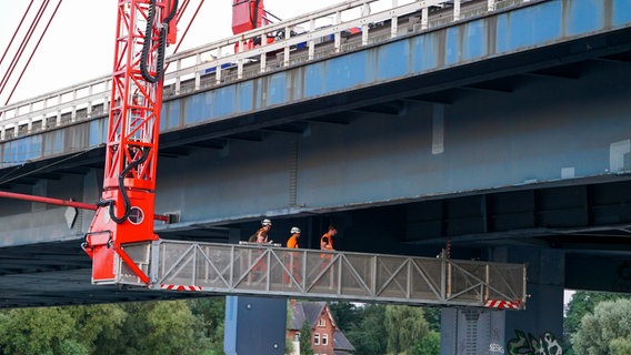 Arbeiter stehen auf einer Hebebühne und überprüfen die Norderelbbrücke von unten. © picture alliance Foto: ABBfoto