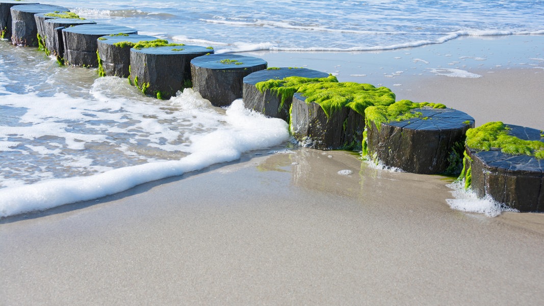 Wasser, Sand und kleine brechende Wellen an der Nordsee.