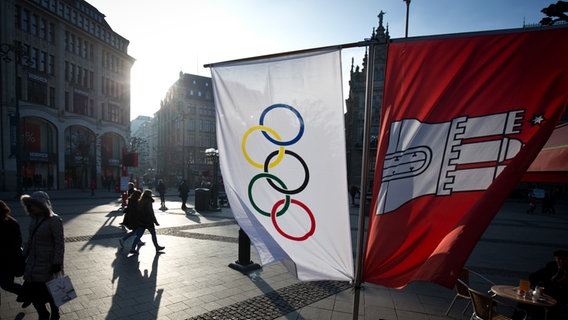 Flaggen mit den Olympischen Ringen und dem Wappen von Hamburg hängen am Rathausmarkt. (Archivfoto) © picture alliance / dpa Foto: Christian Charisius